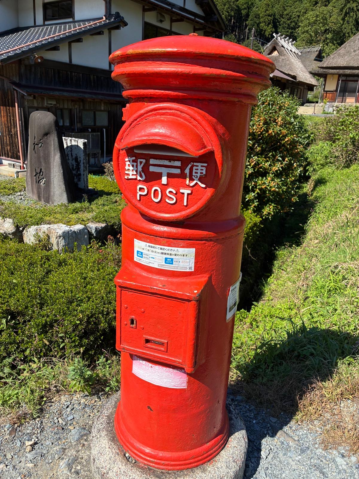 A red postbox in front of the thatched houses