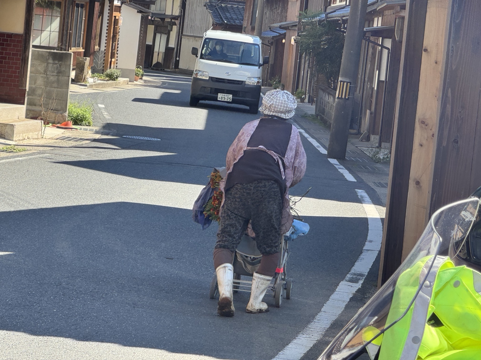 A woman pushes a cart along a narrow street