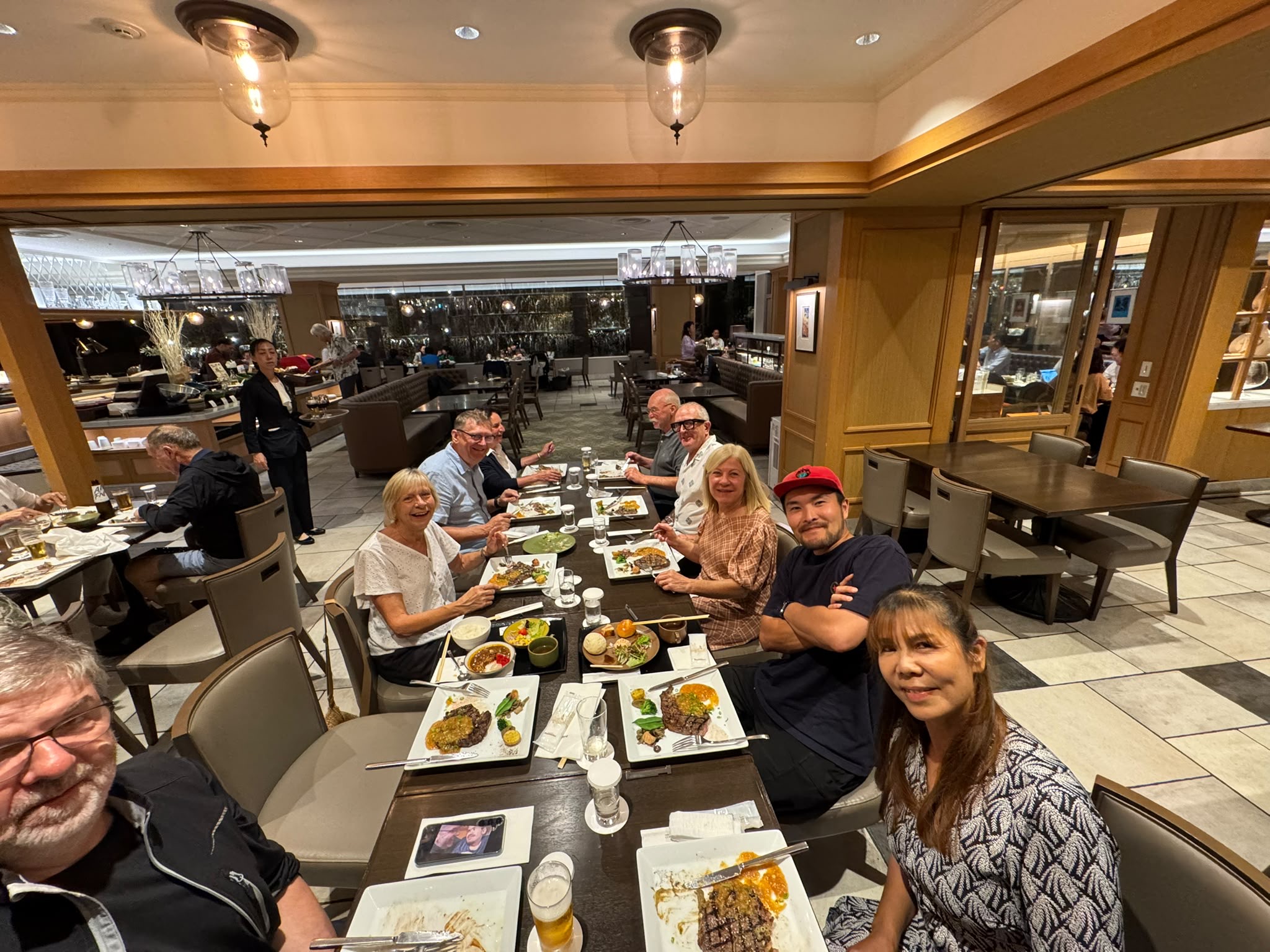 Travel group seated at a long restaurant table set for a meal.