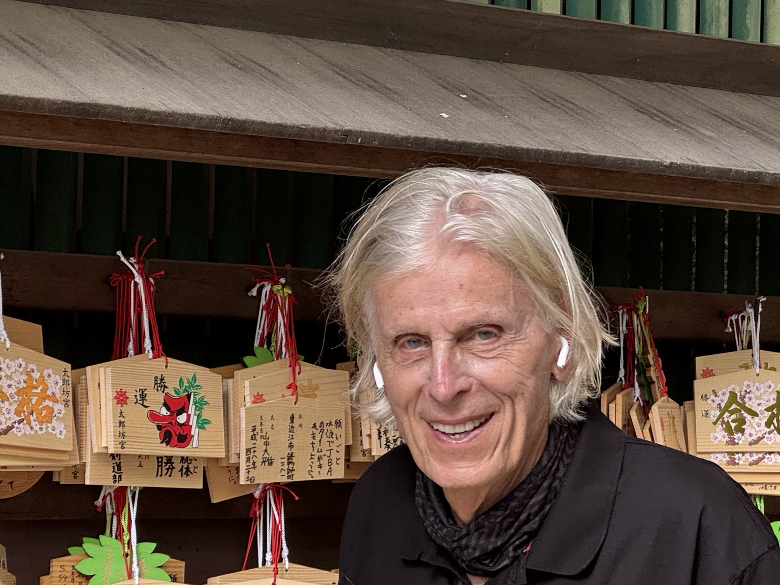 Kurt beside wooden votive plaques at the shrine.