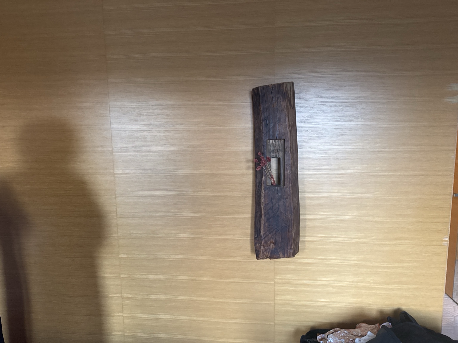 A slender wooden vase decorating the wall.