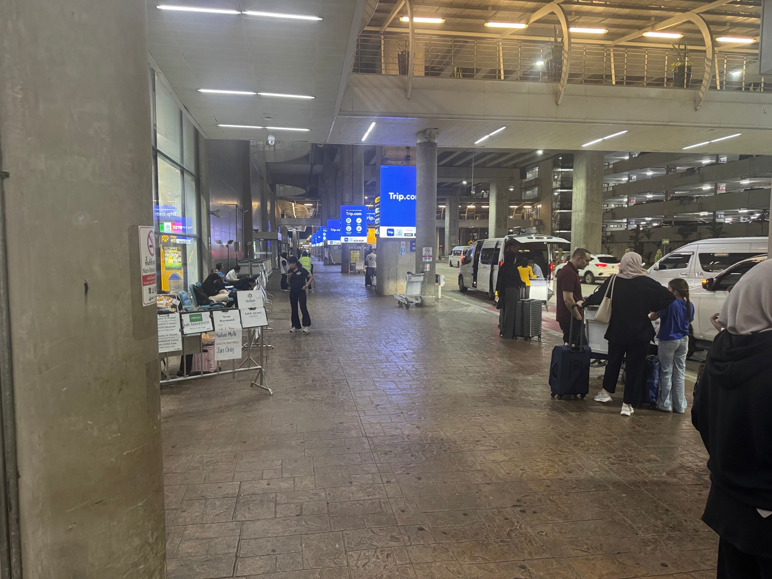 Travellers and luggage outside the airport building.