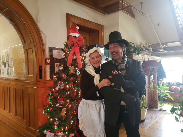 Two guests in Victorian dress and top hat beside the holiday decorations