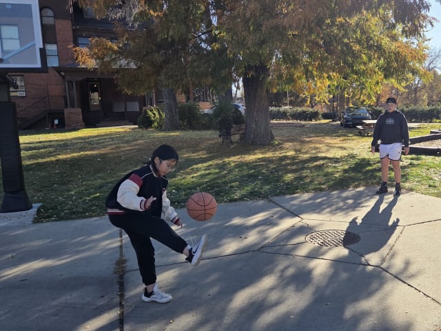Students playing basketball on the outdoor court on an autumn afternoon
