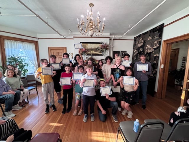 Award recipients holding their certificates as families look on