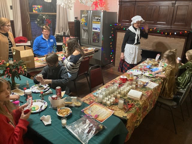 Families making crafts and decorating candles at long tables