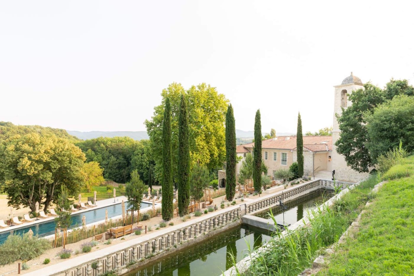 Facade of Le Couvent des Minimes in Mane, water basin, cypress trees and terraced gardens below the bell tower