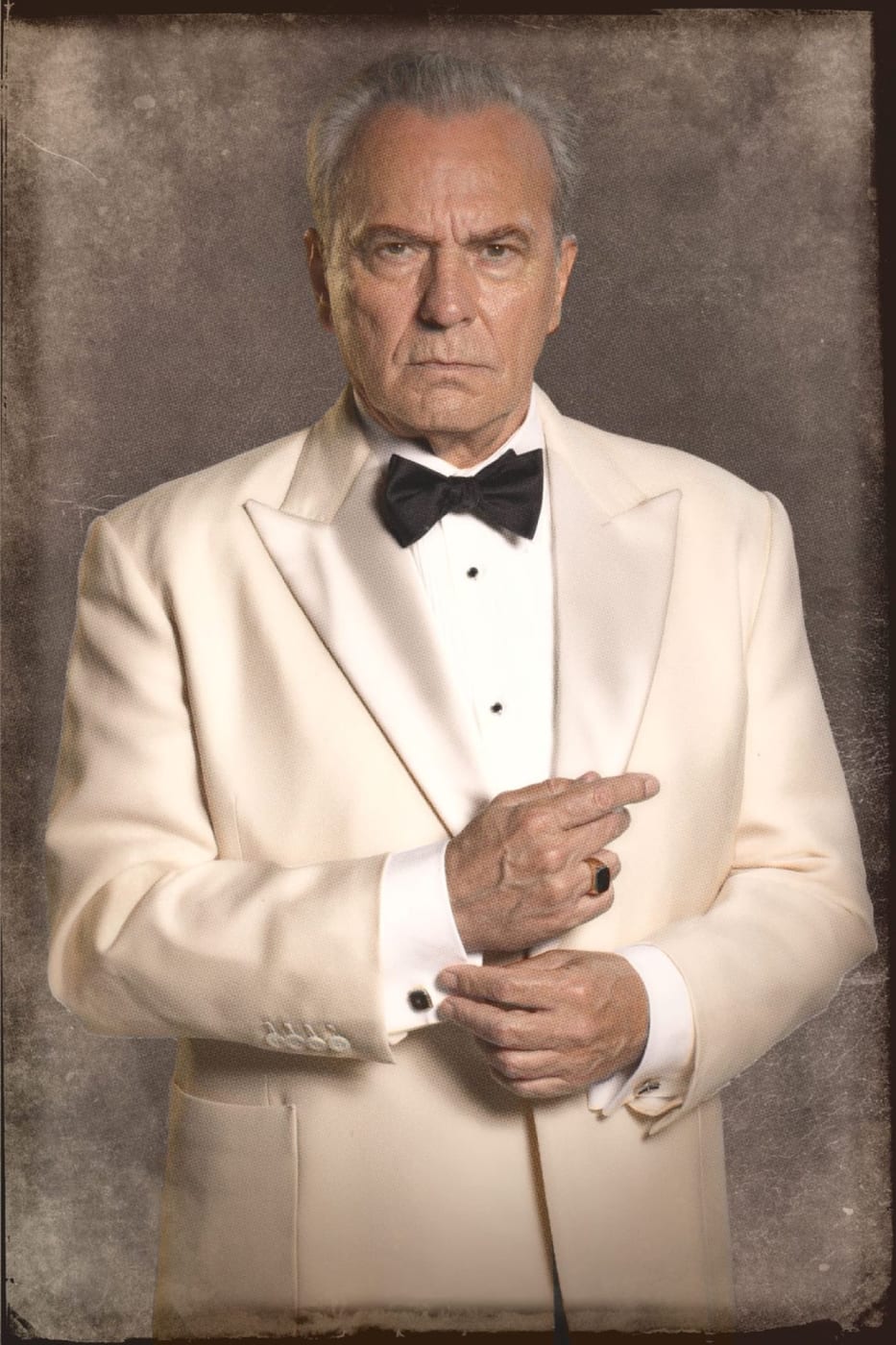 Retrato de José Coronado em smoking branco, cartaz de personagem de El problema final