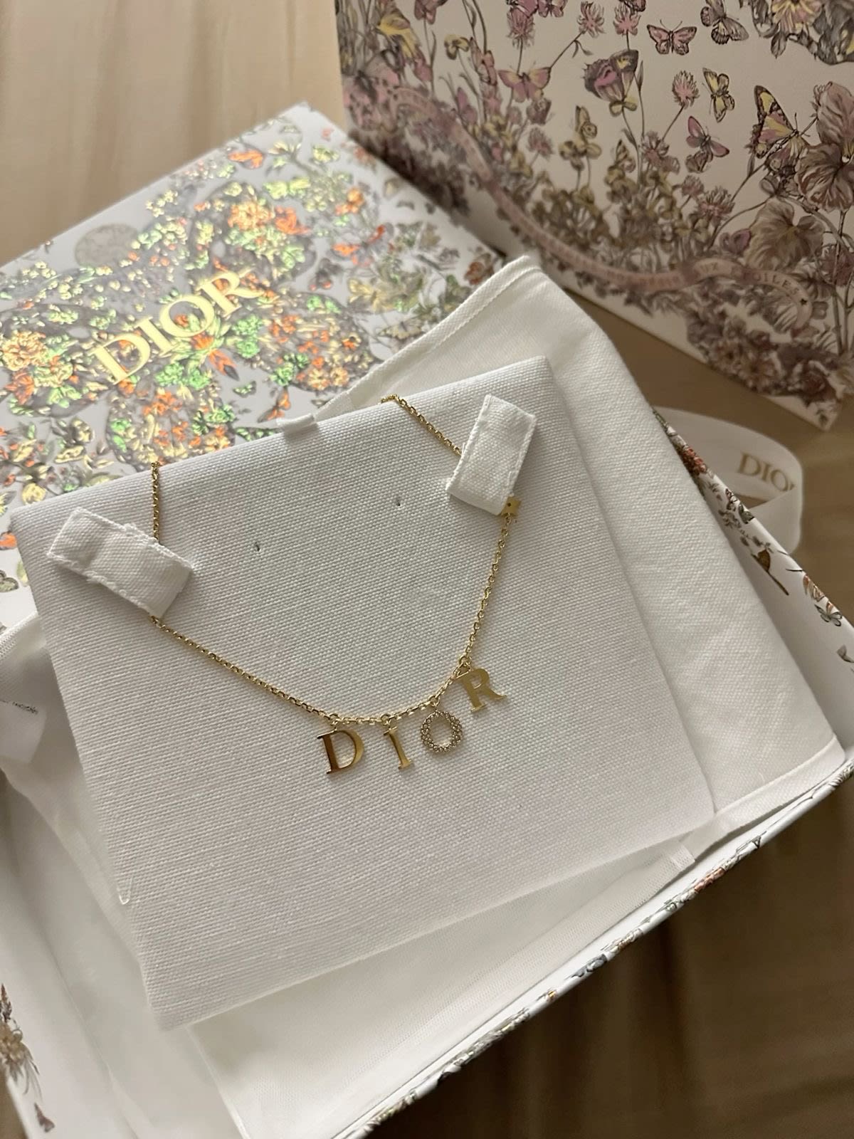 Gold Dior lettering necklace and earrings on a display card
