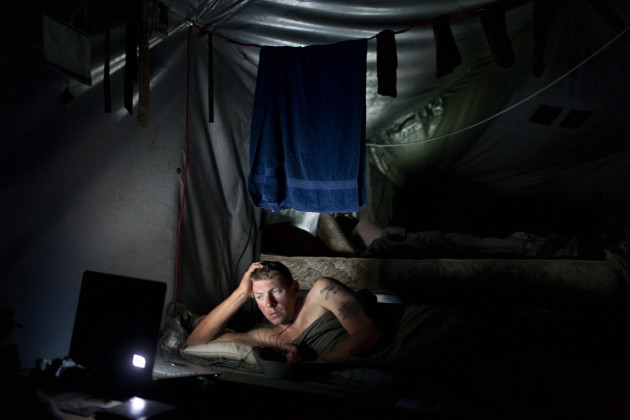 A US Army soldier watches a laptop computer in his tent at Combat Operations Post Tangi, in the Tangi Valley, Wardak Province, Afghanistan, 2009.