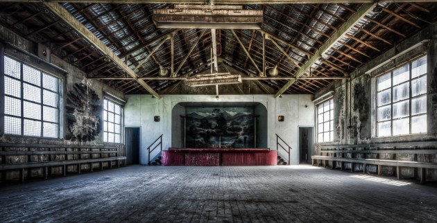 Entertainment room. This is at the Victoria Road entrance to the plant. A big, long room where the hard-working power plant staff cooled down after a hard day next to the furnaces. Kind of looks like the ultimate man cave in a power station 50 years ago. It has built-in speakers in the walls, a kitchen and even still a couple of old ping pong tables and something that looks like table soccer but from 50 years ago. No Wi-Fi unfortunatley. Notice the old murals on the wall and the stage? Most of the side wall murals have been washed away from when the asbestos roof was removed a few years ago. © Brett Patman