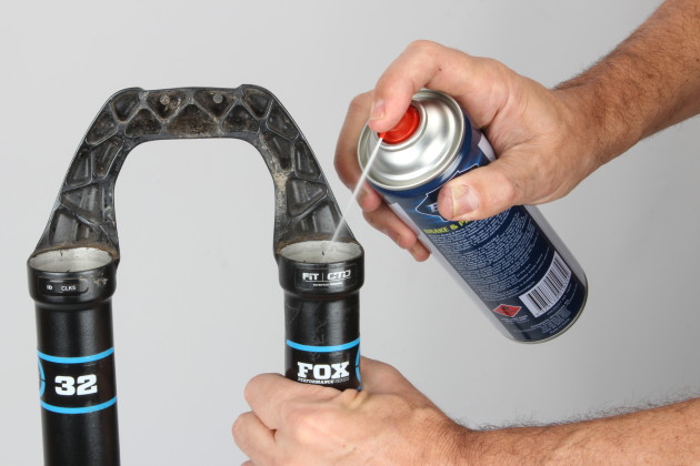 Now you should be holding an empty lower leg assembly with nothing but the bushings inside. Spray alcohol or disc brake cleaner inside and use a bottle cleaning brush to scrub inside—this will help to dislodge any dirt or contaminants. Alcohol is better than degreaser as it won’t leave any residue.