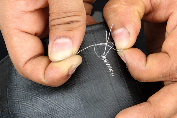 <p>Continue stitching the tyre as shown. Once you’ve gone the full length of the cut, start working your way back until you’ve used up most of the thread. When there’s only 20-30mm left, snip the thread and tie the two ends in a knot on the inside of the tyre casing. Trim the excess thread but don’t go too close to the casing—it’ll be on the inside anyway, so nobody will see it. Your tyre will look a bit like a Frankenstein experiment from the outside but it should be nice and strong; pull and stretch the casing to check that it’ll hold together.</p>