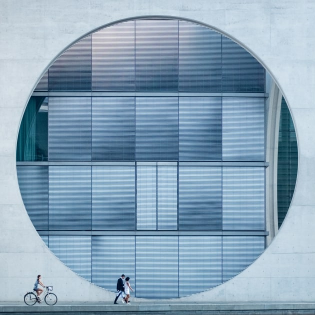 Having just arrived in Berlin on a bright summer's day, my wife and I decided to take a morning walk along the River Spree. We soon came across a large concrete building, and I was immediately struck by its geometry and scale. Across the river, I positioned myself for a single point perspective and waited for the right moment to capture it. A couple came into the viewfinder and I noticed the cyclist out of the corner of my eye. I waited for them to move into the frame and hit the shutter to try and balance the composition. Copyright: © Tim Cornbill, United Kingdom, 1st Place, Open, Architecture, 2017 Sony World Photography Awards.