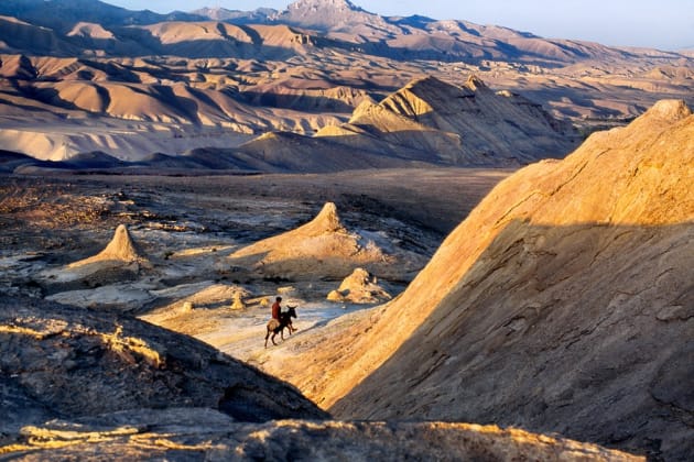 Bamiyan province, 2006. A man rides a donkey through the desert.