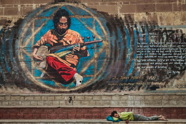 An Indian man asleep on the steps by the River Ganges, Varanasi, India. The painting on the wall grabbed my attention first before I noticed the man sleeping. I composed the image around the painting, placing the man in the bottom right third of frame with the man in the painting looking down on him. This gives the image balance and a connection between the two figures. Canon 6D, 24-105mm @ 67mm, 1/400s @ f/5.6, 400 ISO, handheld. Contrast, curves, saturation and levels adjusted in Adobe Lightroom.
