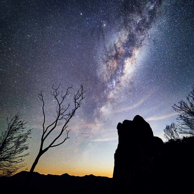 The Warrumbungles, NSW, is now designated as a dark sky reserve. I noticed these fire-ravaged trees pointing back towards the imposing figure of Belougery Spire, with the Milky Way behind. Sony A7S, Samyang 14mm f/2.8 lens, 25s @ f/2.8, ISO 6400, tripod.