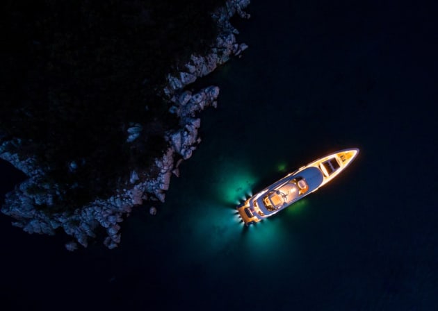 Night lights by jeff. A private superyacht stands out with its lights in the dark waters at night from above.