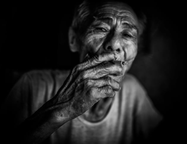 An elderly man smoking a cigarette in his home in Hoi An, Vietnam. Converting from colour to monochrome helped define the wrinkles on his face to create interesting textures. Underexposing the background eliminated any unwanted distractions.
Fujfilm X100S, fixed 35mm lens. 1/800s @ f2, 
ISO 400. Monochrome conversion, contrast and clarity adjusted in Adobe Lightroom.