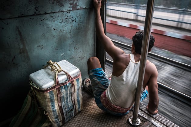 Worker on his way home on the locals’ train in Kolkata, India. I slowed my shutter speed down enough to blur the tracks through the doorway while focusing on the man for a sharp visual. Fujifilm X-E2, 18-55mm lens @ 18mm, 1/20s @ f11, ISO 200, handheld. Contrast, curves and levels adjustment, sharpening in Photoshop CC. Photo © Drew Hopper.