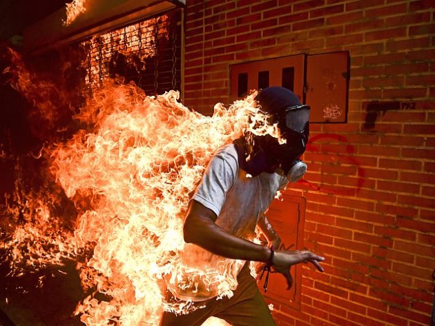 The World Press Photo of the Year. © Ronaldo Schemidt.
‘Venezuela Crisis’. May 3, 2017. José Víctor Salazar Balza (28) catches fire amid violent clashes with riot police during a protest against President Nicolás Maduro, in Caracas, Venezuela.
President Maduro had announced plans to revise Venezuela’s democratic system by forming a constituent assembly to replace the opposition-led National Assembly, in effect consolidating legislative powers for himself. Opposition leaders called for mass protests to demand early presidential elections. Clashes between protesters and the Venezuelan national guard broke out on 3 May, with protesters (many of whom wore hoods, masks or gas masks) lighting fires and hurling stones. Salazar was set alight when the gas tank of a motorbike exploded. He survived the incident with first- and second-degree burns.
Commissioned by Agence France Presse.