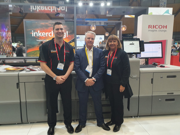 (from left) Michael Leins, Ricoh; Walter Kuhn, Kuhn Corp; and Roberta Van Trier, Ricoh, show off the Pro C7210x press.