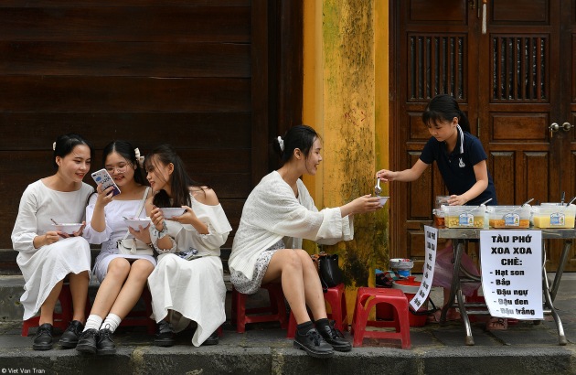 Street Food, Viet Van Tran, Vietnam. Enjoying Hoi An old town, a popular tourist destination in central Vietnam (recognized by UNESCO as world cultural heritage), where there are many delicious sweet soup. Four young girls were passionately eating sweep soup made me feel that life is lovely even though we are all living in a pandemic.