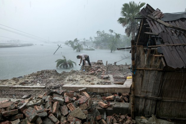 © Zakir Hossain Chowdhury. A man collects bricks from his house, which is submerged by daily tides. “Our embankment collapsed and our houses have eroded,” said Habibur Rahman Sarder, 56. “We have no space to live, no space to cook food, and no place to grow food.”