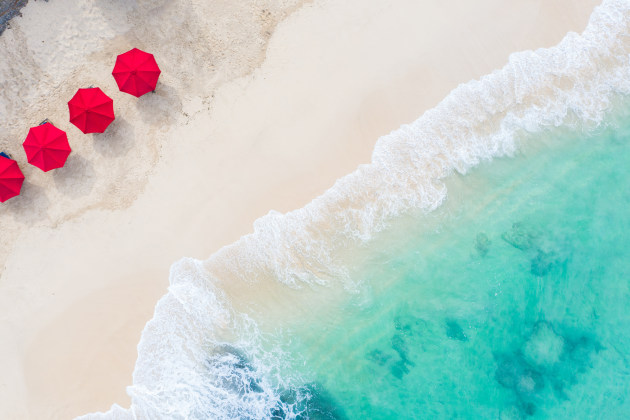 Aerial photo of red beach umbrellas by the sea