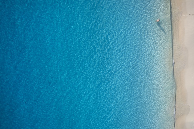 © Craig Parry. Lost in the Pacific. “An image of my wife in what seems the middle of nowhere. The use of negative space from above can have its benefits especially a scene like this. The footprints leading into the water and the hues of the blue spectrum make this one of my favourite drone images.”