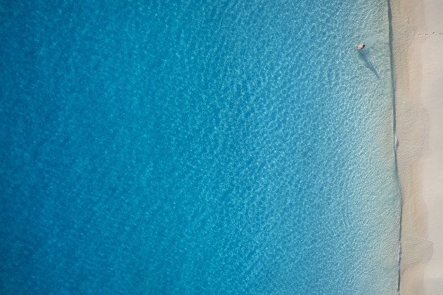 © Craig Parry. Lost in the Pacific. “An image of my wife in what seems the middle of nowhere. The use of negative space from above can have its benefits especially a scene like this. The footprints leading into the water and the hues of the blue spectrum make this one of my favourite drone images.”