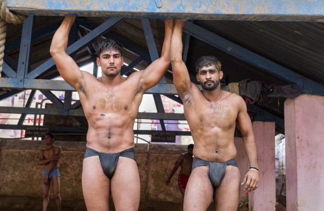 These two wrestlers had just completed a three-hour workout, after which they wrestled each other. They used the bar to stretch out and cool down, and after chatting with them, they were comfortable being photographed wearing the traditional langot. The kushti (mud wrestling pitch) with a man pulling a slab of concrete in the background makes the perfect backdrop, adding depth to their story. ​Fuji X-Pro2, 16-55mm f/2.8 lens
@ 16mm. 1/100s @ f2.8, ISO 2500. -0.33 EV.