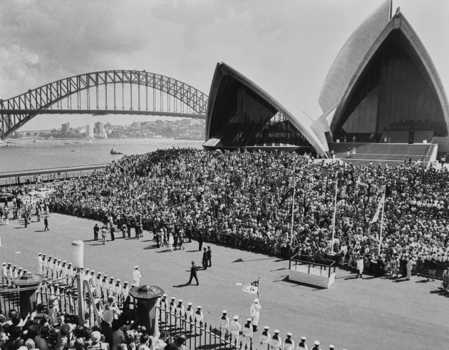 A high-angle view of crowds attending the visit of British Royals Elizabeth II and her husband, Prince Philip, Duke of Edinburgh, to Sydney Opera House on Bennelong Point in Sydney Harbour, Sydney, New South Wales, Australia, 13th March 1977. Designed by Danish architect Jorn Utzon, the Expressionist performing arts venue is staging a production of Benjamin Britten's opera 'Albert Herring' for the Royal Couple who are on a Royal Tour of Australia as part of the Silver Jubilee celebrations. (Photo by Keystone/Hulton Archive/Getty Images)