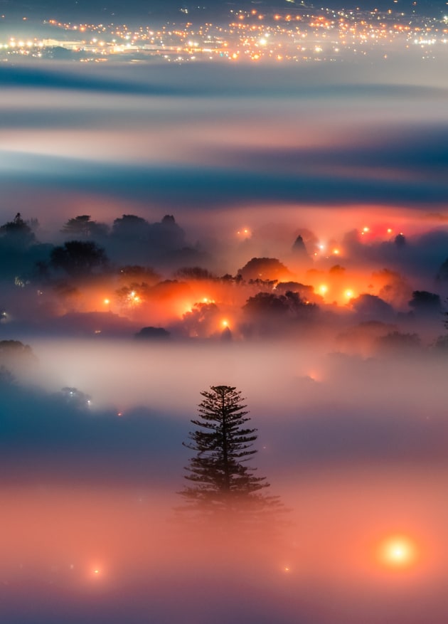 © Jana Luo. Waking up in the fog. "That was a cold morning. I woke up and opened the curtain seeing a very thick fog blanket outside, jumped up and grabbed my gear and went up to the nearby summit. I saw the city was surrounded by the fog blanket, the lights from the streets were more romantic than normal. My city looked so dreamy."