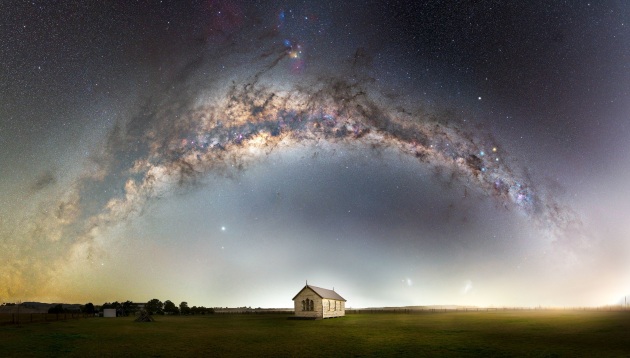 © John Rutter - “Heavens above” 
Hunter Valley, NSW – Australia
This old church sits peacefully in a paddock in the Hunter Valley of NSW, Australia.
That night, the forecast was for terrible weather, so I had written the night off and went home. To my amazement, the skies cleared and it was a race to get back to the location and start shooting. As the fog started rolling in towards the end of the capture, a perfectly timed car drove past to illuminate the scene and the fog.
My passion is bringing the full Milky Way arch into people’s homes via large panoramas. I would encourage everyone to head out to a dark sky and experience it. Camera or not, it is a truly amazing sight to stand under the full arch of the Milky Way.