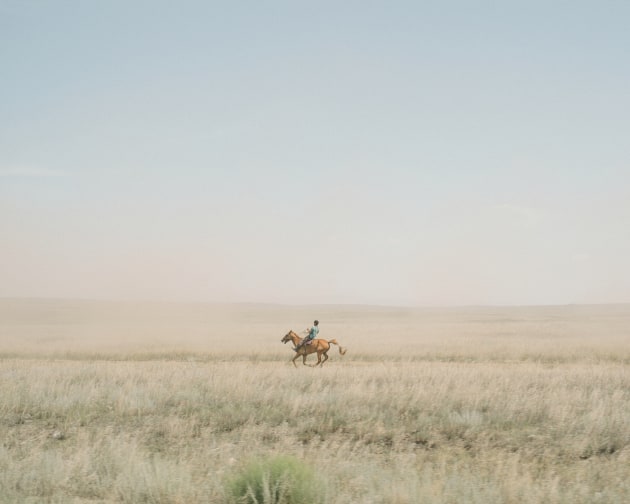 © Nanna Heitmann, winner of the Sunday Times Award for Achievement, 2019. A traditional horse race of the Tuvinese National Festival Naadym in the steppe, at 43 degrees. The horses and their riders cover a distance of 30km. Seven horses died in the heat. Yenisei River, Russia, 2018. From the series, Hiding from Baba Yaga.