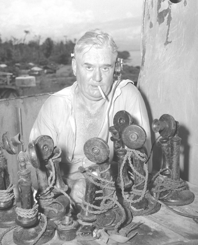 Image: John F. Hoile with telephones in his engineering workshop in the shell of the Japanese ship 'Myoko Maru,' near Lae, New Guinea, People Magazine, February 1951, from film negative. Photographer unknown.