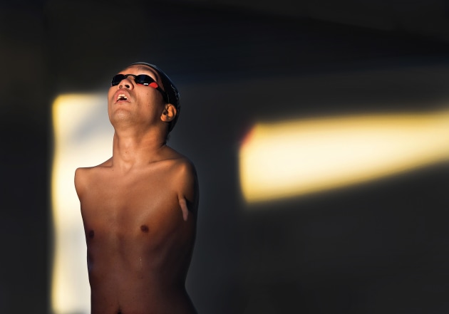 Japanese amputee paralympic swimmer Tomotaro Nakamura looks towards the setting sun and steels himself as he prepares on the block for the start of his S5 50 metre freestyle final at the 2018 Para Pan Pacific Championships at the Tobruk Pool in Cairns Australia. Nakamura, who had both arms amputated below the shoulder at birth, won Gold. He is one of Japans most accomplished paralympic swimmers. Nikon D5, Nikkor 400mm f2.8 lens. 1/1600s @ f5, ISO 800.