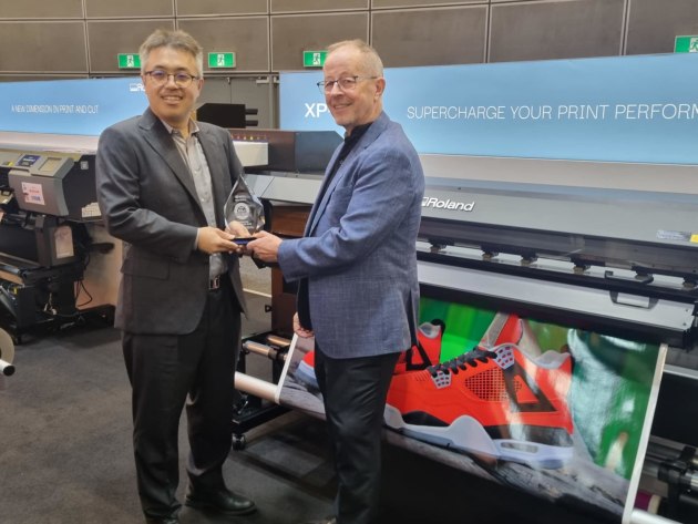 Toru Tamauchi from Keypoint Intelligence presenting the trophy to Roland DG Australia's John Wall.
