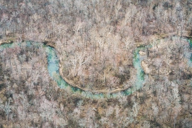 © Peter van Agtmael. Illinois, USA. 2017.
“In the winter of 2017, I was in southern Illinois documenting the environmental consequences of coal mining in the region. I rented a helicopter to survey damage that was hidden from view. From above, the world can become simultaneously richer and more intangible, as the eye takes in far more details, sweeping across the scene, than it can easily distill. For me, the camera is not so well suited to the vastness of the landscape, but can render its details in ways that are both abstract and descriptive. After I photographed the surface mining and the polluted runoff, I had a few minutes left. The pilot clearly loved to fly, and through a microphone I guided him to where my instinct took me. I found this bend in a creek surrounded by bare trees.”