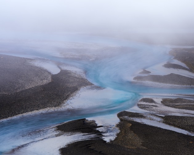 Poulter River, Arthurs Pass, New Zealand. A misty morning over the Poulter River where water blends into sky, the vivid blue glacial flow contrasting against the dark gravel banks. A simple but striking study in tone and colour. Nikon Z8, Nikkor 300mm f4 lens, 5s @ f8, ISO 32.