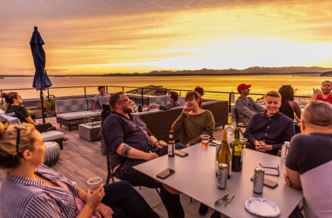 Dinner Party on Rooftop Overlooking Sunset and Seattle Waterfront at 10 Clay Apartments in Seattle, WA