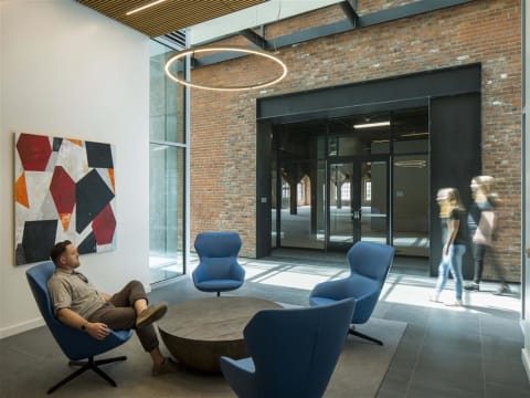 Lounge Area with Four Blue Chairs Circled Around a Coffee Table in Co-working Building With Modern Art Decor at 10 Clay Apartments in Seattle, Washington