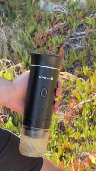 La cafetera portátil Noirpress al aire libre, con el vaso servido