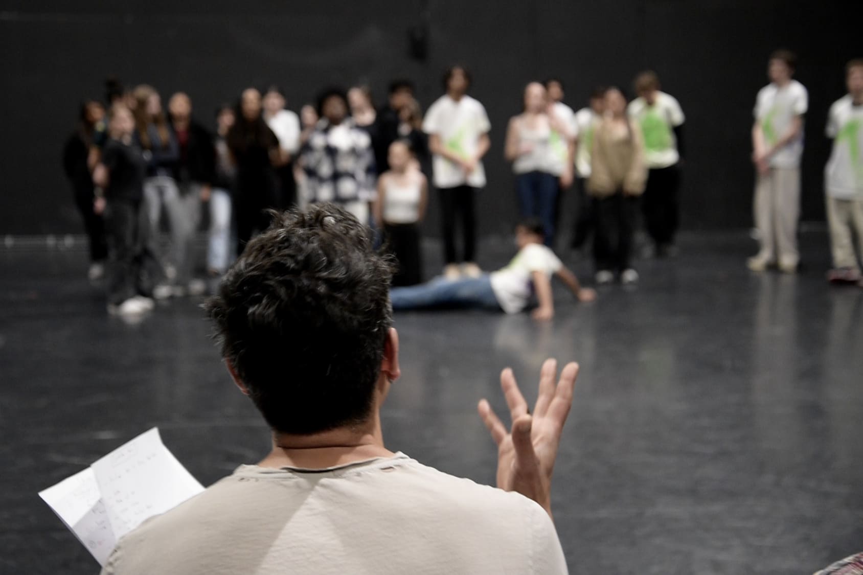 A member of Y-Collective stands in front of a group of high school students, giving performance notes and cues during a rehearsal.