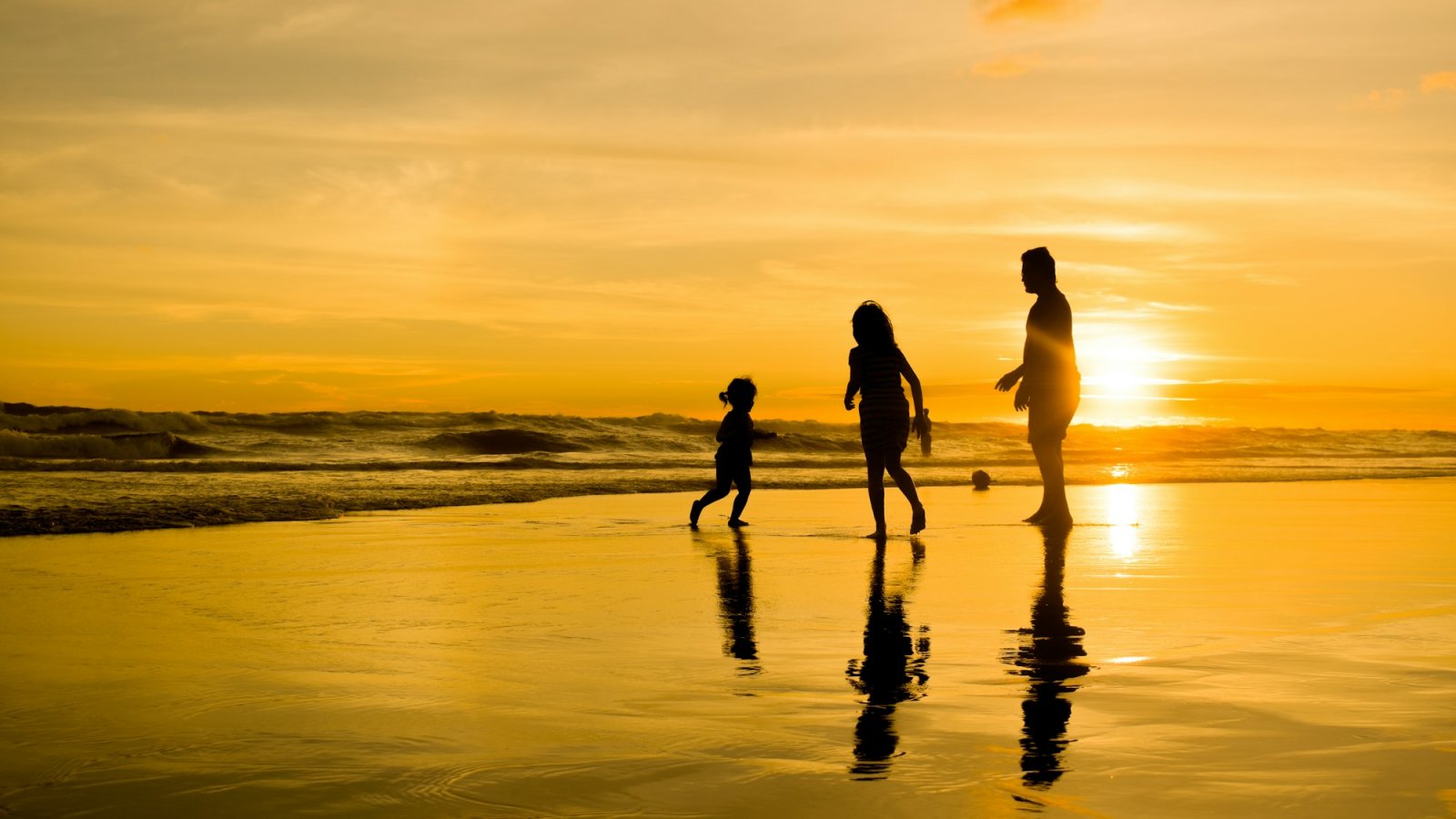 Familia caminando junta en la playa al atardecer
