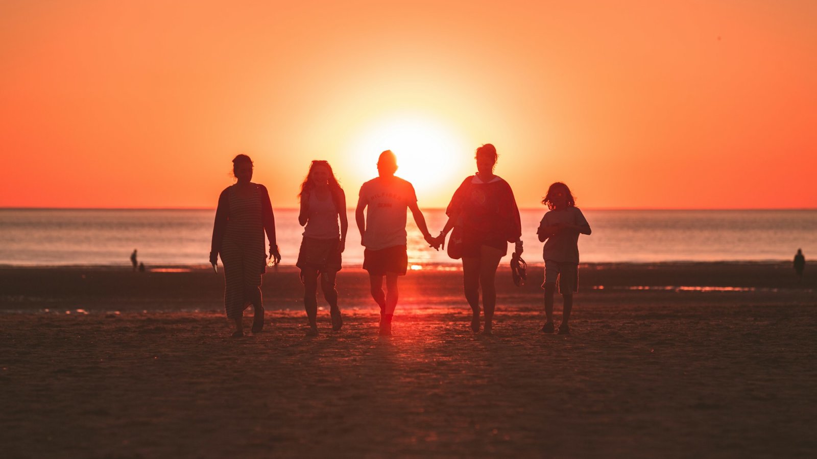 Familia caminando por la playa al atardecer en verano