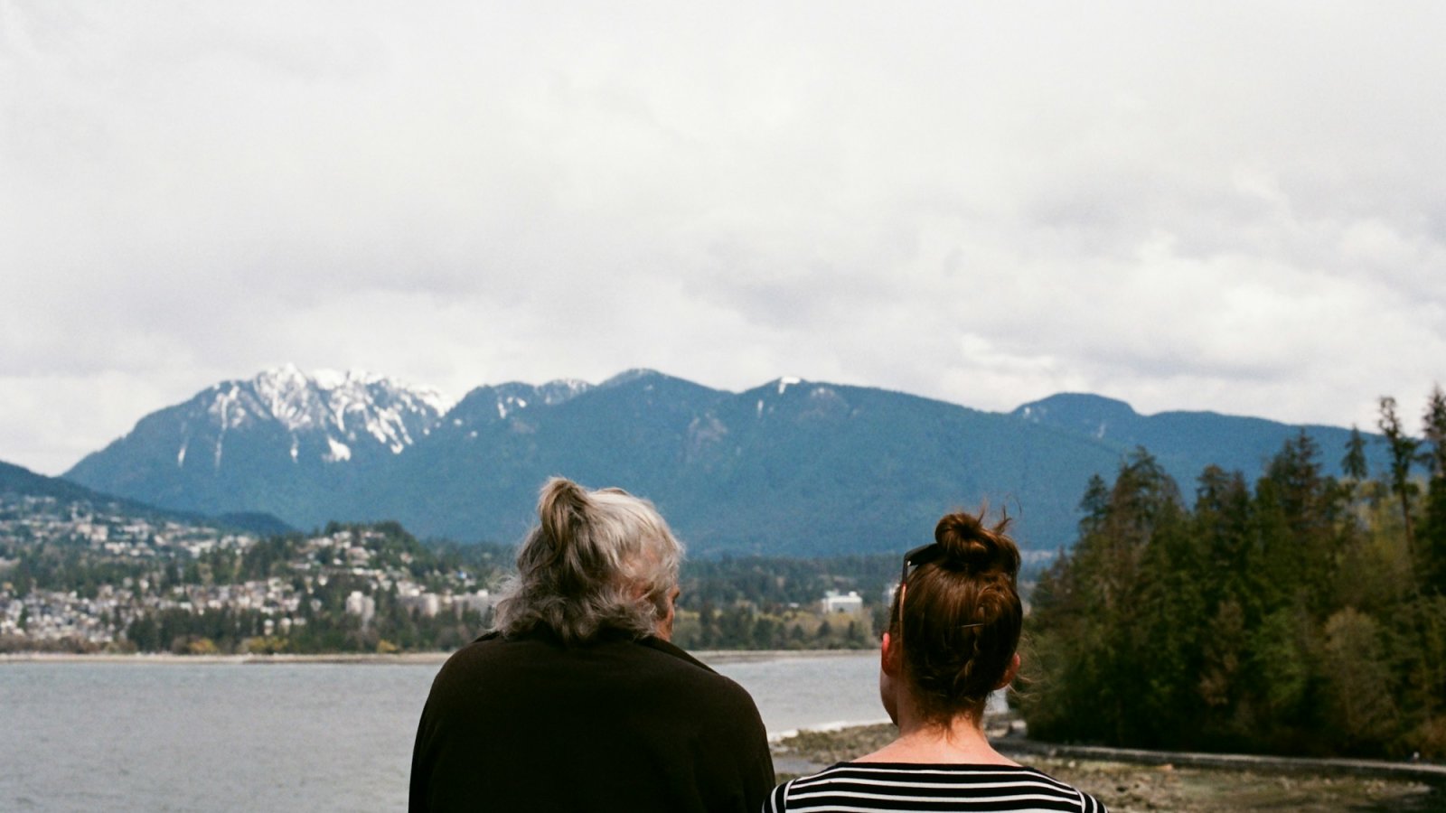 Madre e hija adulta contemplando montañas y mar durante un viaje