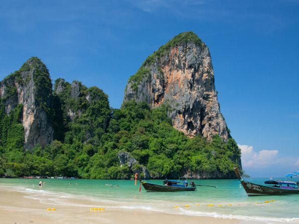 Barcas de cola larga en la playa de Railay bajo acantilados de piedra caliza, Krabi