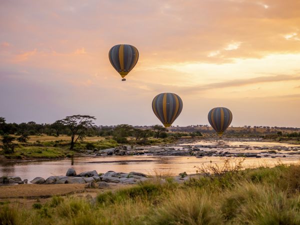 Globos aerostáticos sobre el río al amanecer en el Serengeti, Tanzania